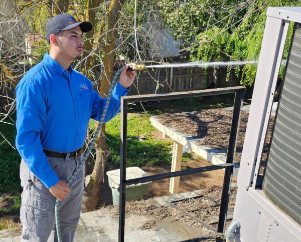 professional hvac technician cleaning residential ac unit in fresno, ca