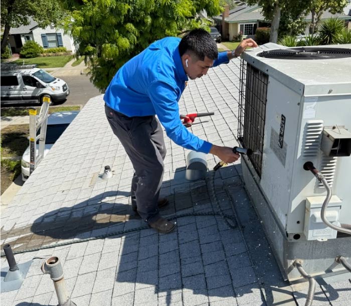 A Mechanical Air technician is shown cleaning an air conditioning unit to improve its performance and efficiency, a key part of maintaining the system.