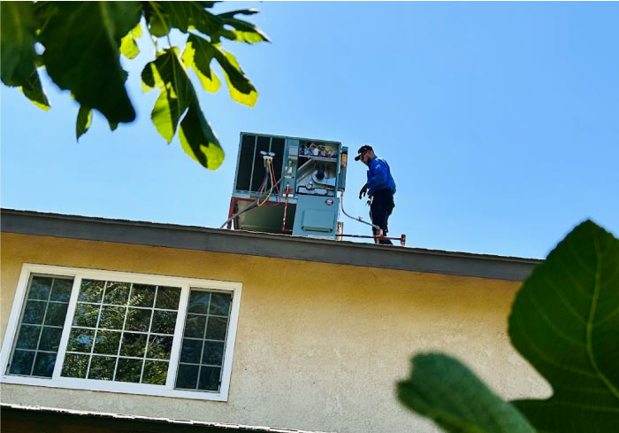 Mechanical Air technician on the rooftop, performing HVAC maintenance on a residential air conditioning unit in Fresno, CA 