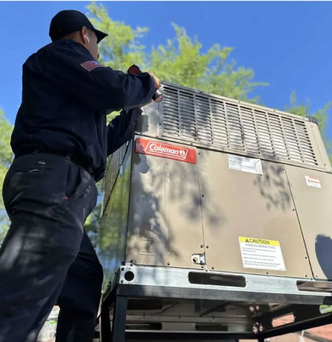 A technician is inspecting or repairing a Coleman branded unit on a roof.