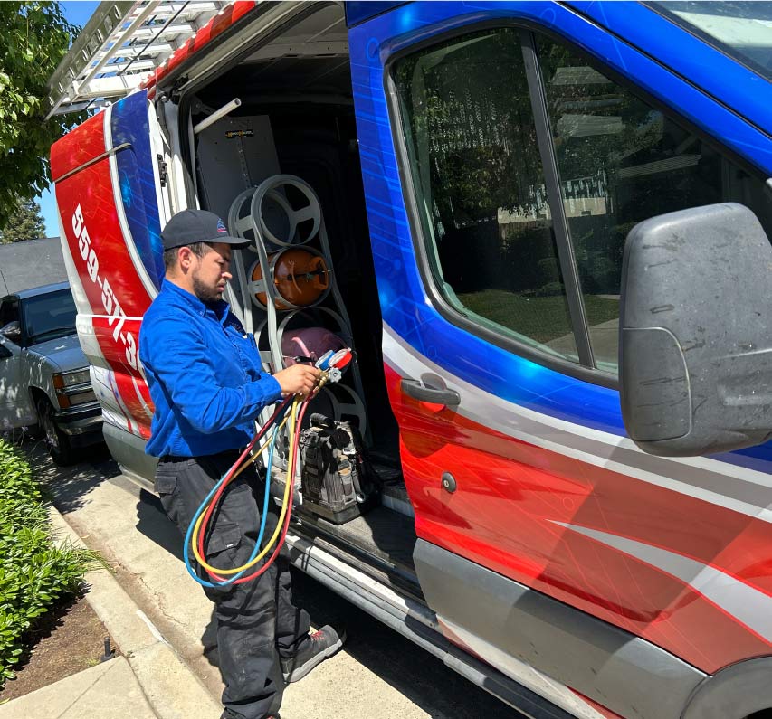 HVAC technician preparing manifold gauges and refrigerant tools from a fully stocked service van for a mini split ac installation
