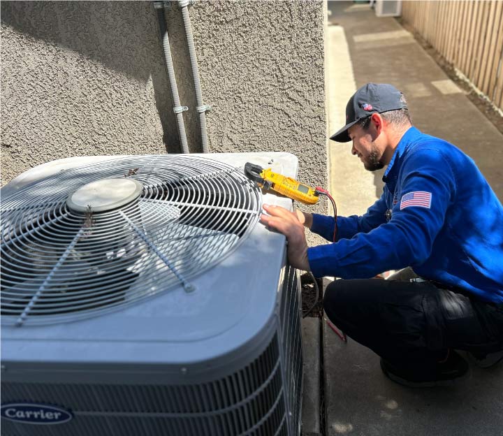Professional AC repair technician using a multimeter to troubleshoot electrical issues on a Carrier residential air conditioning unit