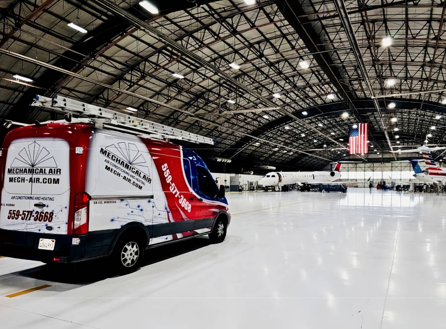 Mechanical Air service van with company branding and phone number 559-577-3668 parked inside a large professional aircraft hangar, highlighting expert commercial HVAC services.