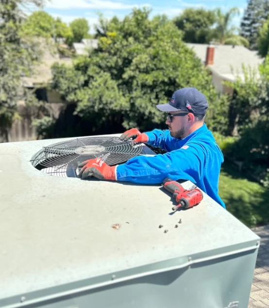 Mechanical Air technician securing the top fan grille on a rooftop AC unit during a residential cooling repair