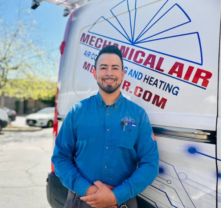 Smiling Mechanical Air company representative in a professional uniform standing proudly in front of a branded service van